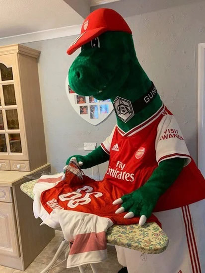 'KEEPING BUSY' Iconic Arsenal mascot Gunnersaurus so bored at home he’s stuck ironing ahead of Bargain Hunt and planting in garden
