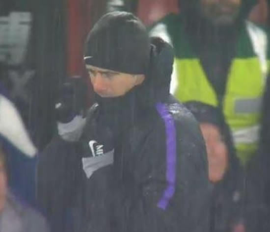 Tottenham boss Mauricio Pochettino cuts his face after struggling with coat in torrential rain